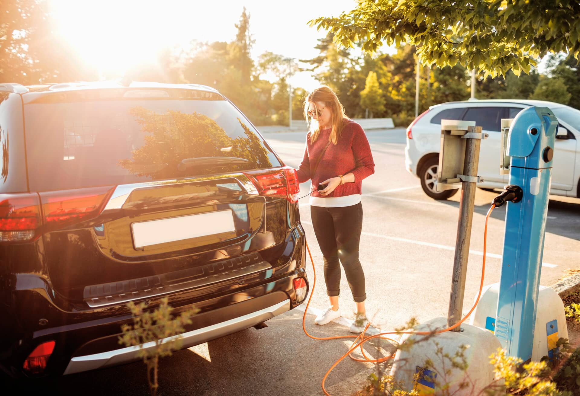 Eine junge Frau, die ein Elektroauto aufladen möchte.